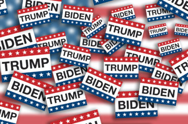 Piles of voting signs with stars and stripes from the American flag and the last names of President Donald J. Trump and Joseph R. Biden flying around on USA flag background. (Photo: AdobeStock)